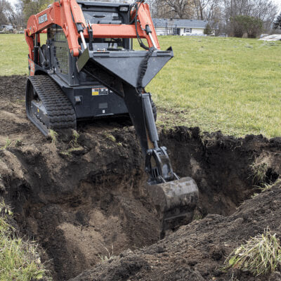 Prime Attachments Backhoe for Skid Steer angled view, orange and black with digging bucket.