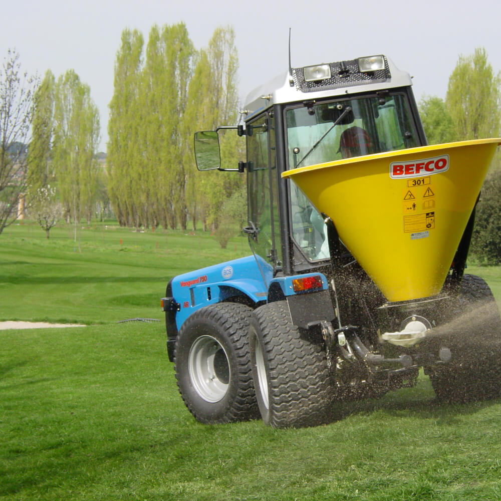 BEFCO Turbo Hop 301 Pendulum Spreader, yellow hopper, angled view, mounted on blue tractor.