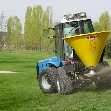 BEFCO Turbo Hop 301 Pendulum Spreader, yellow hopper, angled view, mounted on blue tractor.
