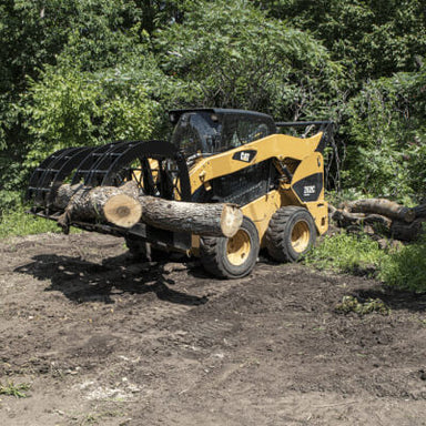 Forestry Grapple for Skid Steer by Prime Attachments, black and yellow, grabbing large logs.