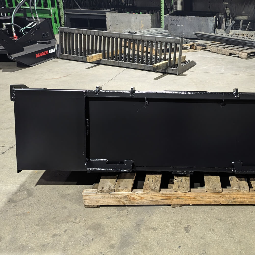 Heavy Duty Bucket for Skid Steer by Glacier Attachments, black, front view on wooden pallet.