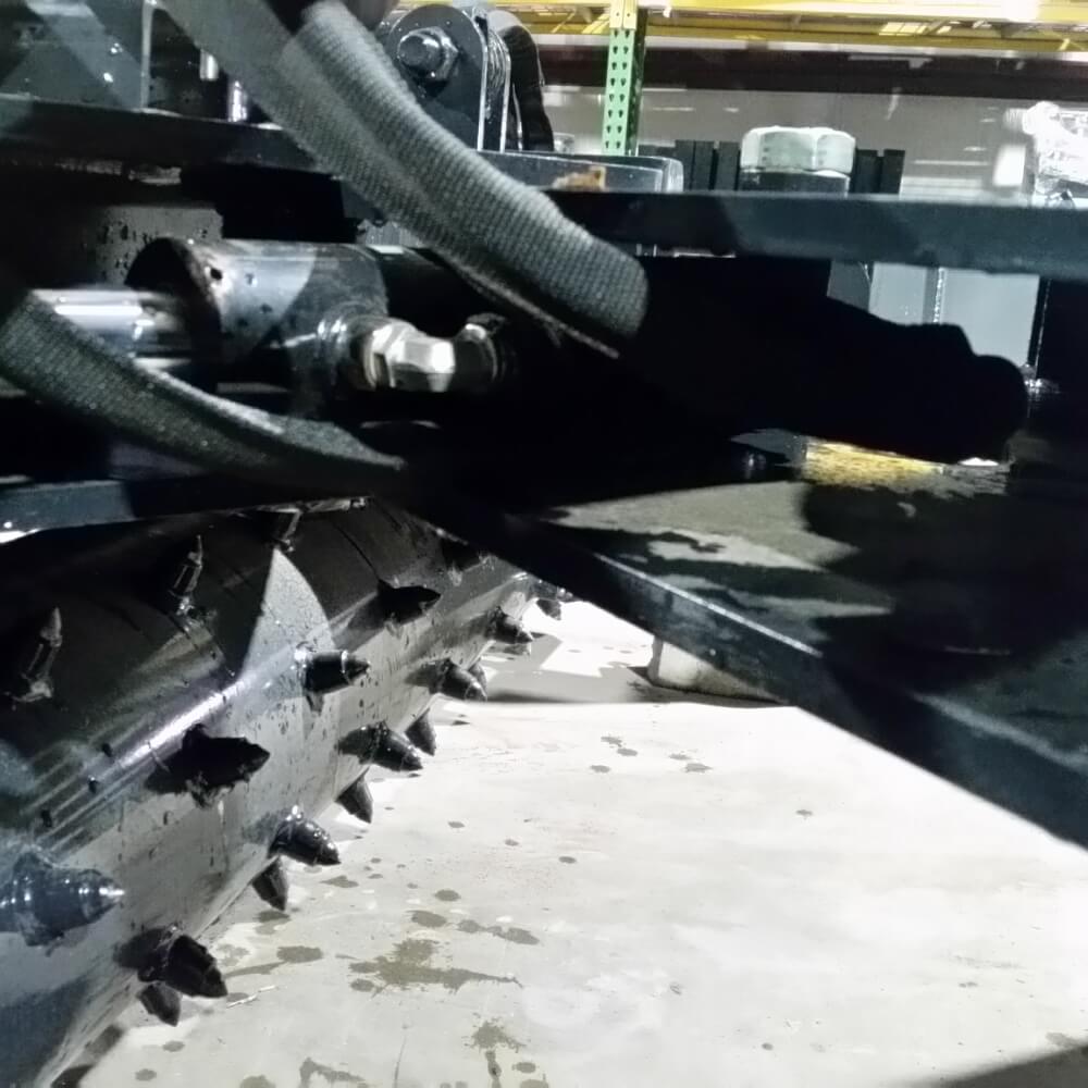 Skid Steer Soil Conditioner by Glacier Attachments, angled view revealing spikes and hydraulic components.