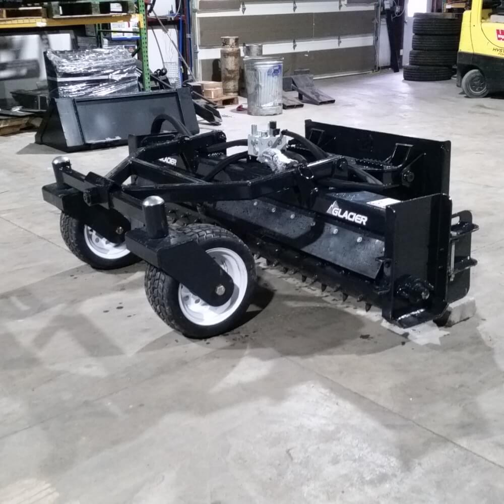 Skid Steer Soil Conditioner by Glacier Attachments, black with wheels and angled view.