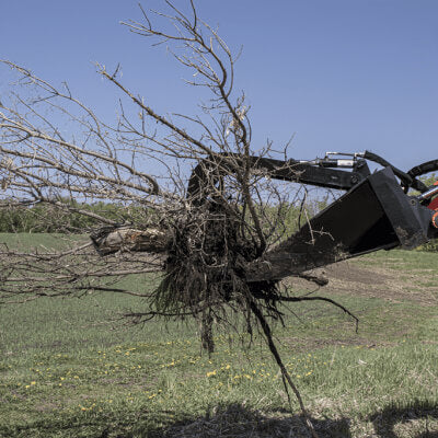 Prime Attachments Skid Steer Stump Bucket Grapple angled view, black, gripping tree stump with roots.