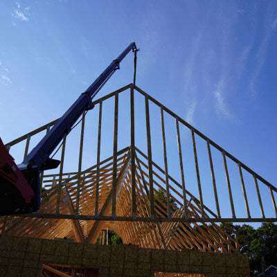 Skid Steer Teleboom by Prime Attachments, angled view with a blue arm lifting construction materials.