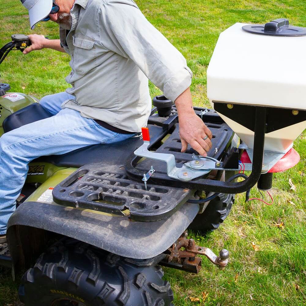 Swisher Commercial Pro ATV Spreader, white hopper mounted on ATV, showcasing adjustable settings and sturdy frame.