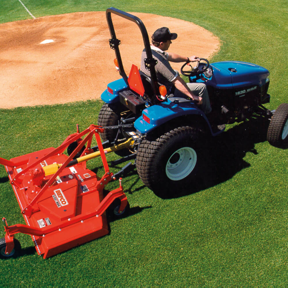 BEFCO C50 Grooming Mower, red with adjustable arms and attached to a blue tractor, angled view.