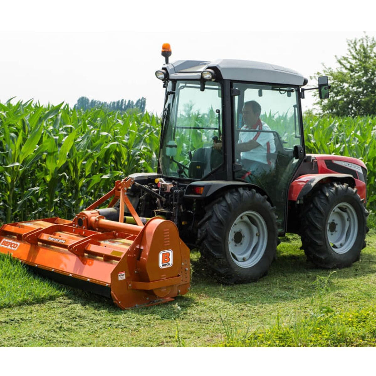 BEFCO Hurricane H70 Flail Mower, orange, angled view, mounted on tractor, cutting grass.