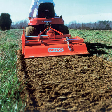 BEFCO T30 Rotary Tiller rear view, bright red with tilling blades engaged in soil.