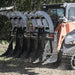 Dual Clamshell Grapple for Skid Steer by Prime Attachments, black with four curved claws, angled view.