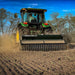 The Firminator G3 cultivator with green and black coloring attached to a tractor, tilling soil.