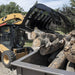 Forestry Grapple for Skid Steer by Prime Attachments, black, angled view, gripping logs.