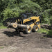 Forestry Grapple for Skid Steer by Prime Attachments, black and yellow, grabbing large logs.