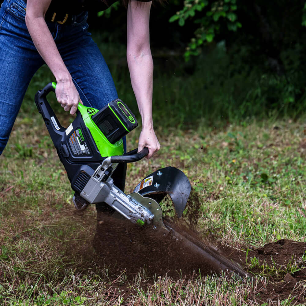 GeoRipper e/B 500 GreenWorks trencher, green and black with handle, cutting through soil.