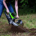 GeoRipper e/B 500 GreenWorks trencher, green and black with handle, cutting through soil.