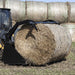 High Capacity Grapple Bucket by Prime Attachments, black, angled view gripping a hay bale.