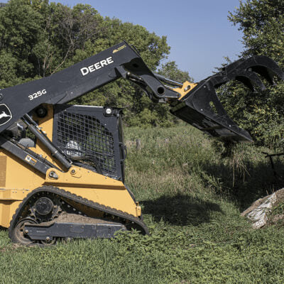 Rock and Brush Grapple by Prime Attachments, angled view, black with claw-like tines for gripping debris.