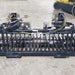 Rock and Brush Grapple Glacier Attachments front view, black with hydraulic hoses and sturdy grating.