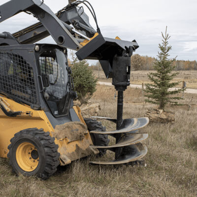 Skid Steer Auger Drive by Prime Attachments, black with triple blades, angled view in operation.