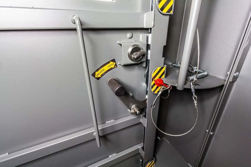 Swisher 6 Person ESP Safety Shelter interior door latch, grey with safety labels and locking mechanism.