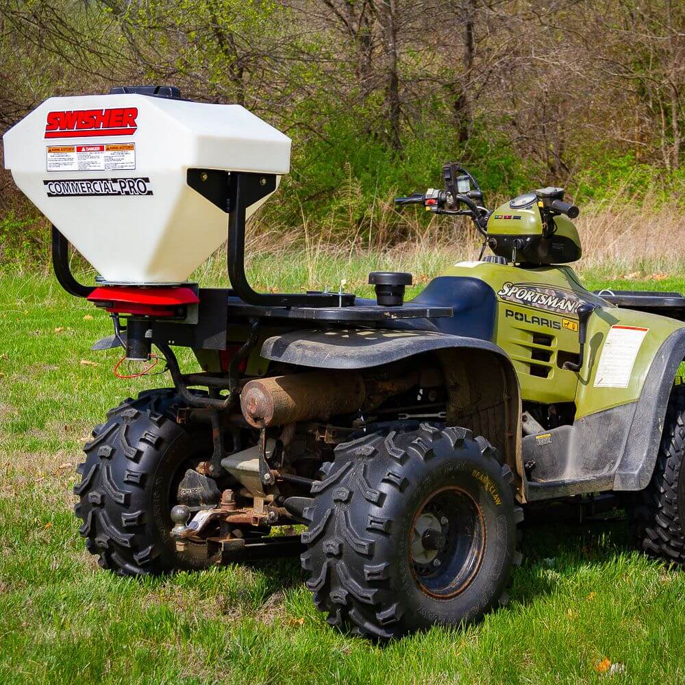 Swisher Commercial Pro ATV Spreader, white hopper on ATV with rugged tires, angled view.
