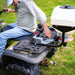 Swisher Commercial Pro ATV Spreader, white hopper mounted on ATV, showcasing adjustable settings and sturdy frame.