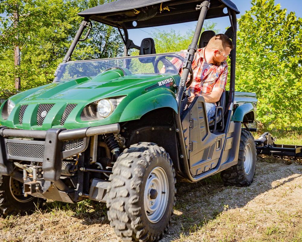 Swisher Commercial Pro RoadBuster Driveway Grader attached to green utility vehicle, showcasing heavy-duty wheels.